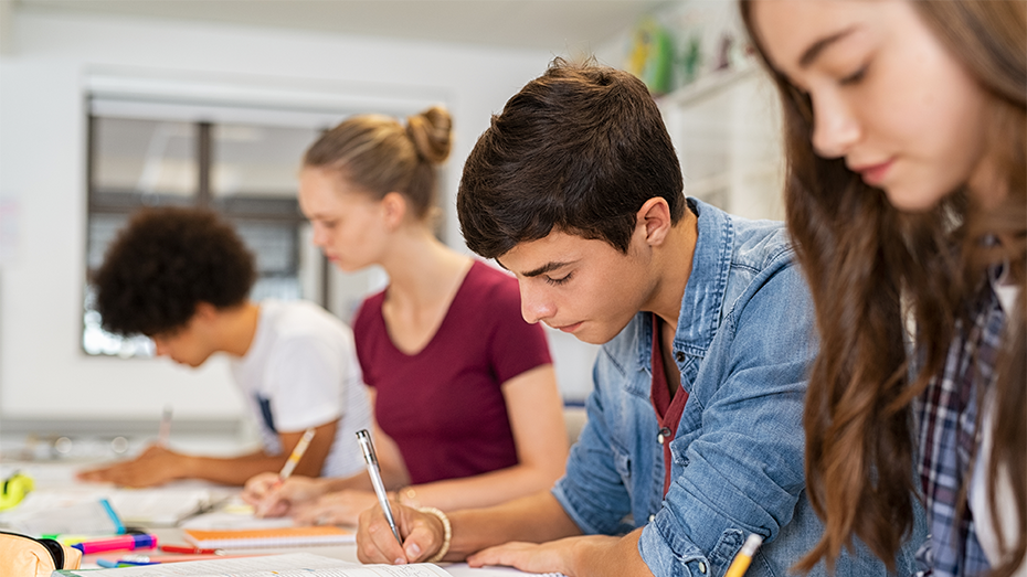 Estudantes com livros e cadernos, em uma sala, estudando para provas.