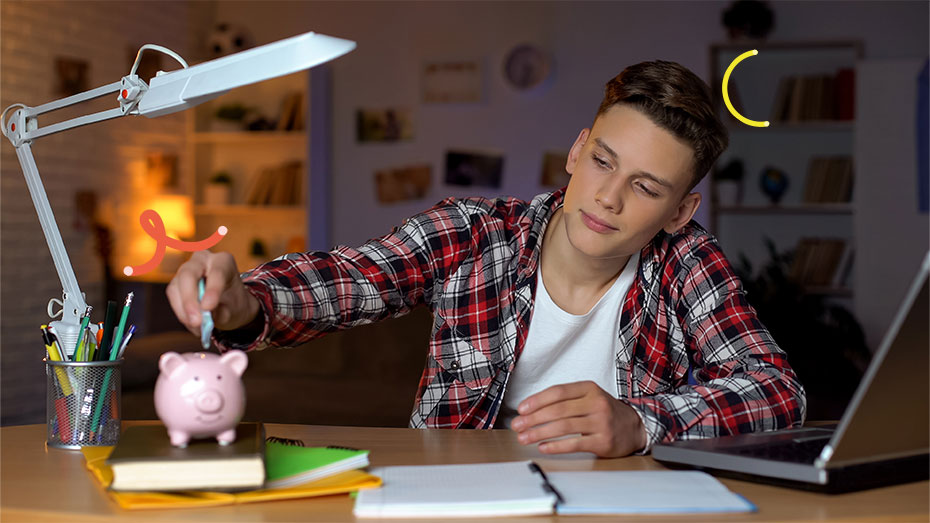 Imagem de um jovem sentado em uma mesa com livros, notebook e colocando dinheiro em um cofrinho.